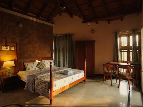 a bedroom with a bed and a desk and a table at EcoMinimalist Home by the River in Seringapatam
