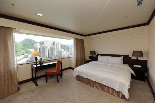 a bedroom with a bed and a desk and a window at Beautiful Hotel Taipei in Xindian