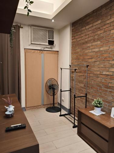 a living room with a fan and a brick wall at LDN Secret Crib 7D-Two palm tree across NAIA Terminal 3 in Manila