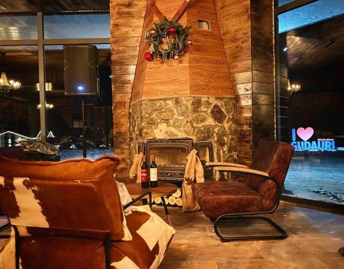a living room with chairs and a stone fireplace at New Gudauri GN Apartments in Atrium in Gudauri