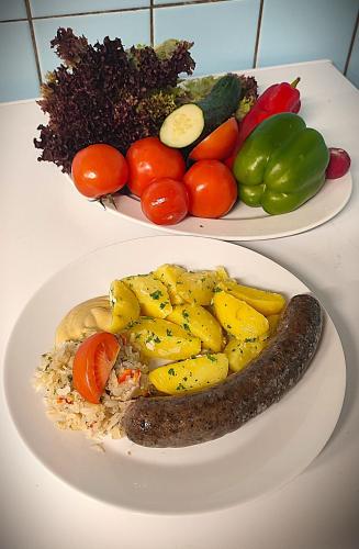 two plates of food with a sausage and vegetables at Pension Helene s mini pivovarem in Kytlice