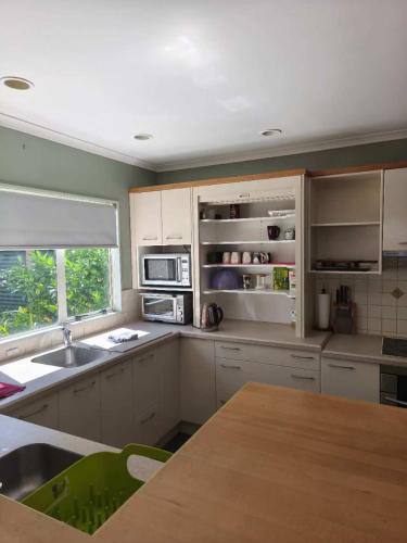 a kitchen with white cabinets and a wooden table at Susan's Holiday House in Hamilton