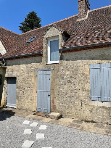 - un bâtiment en pierre avec deux portes de garage et deux fenêtres dans l'établissement Charming Percheron house, à Nocé