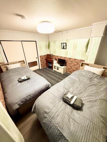 a bedroom with two beds and a television in it at Guest House平安 in Nagoya