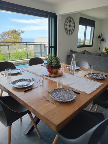 a wooden table with plates and glasses on it at L'Anse des Baleines, Vue panoramique sur l'océan, Piscine & Confort 4 étoiles in Petite Île
