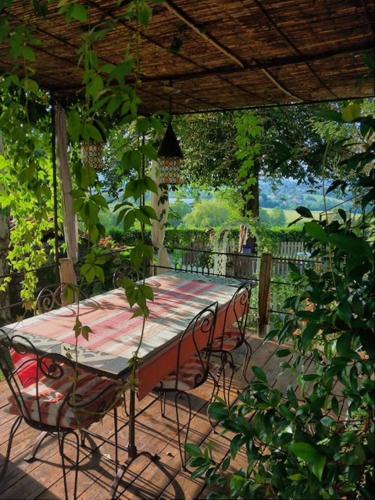 un patio avec une table et des chaises sous une pergola dans l'établissement la maison d'Anna chambres d hôtes, à Ganac