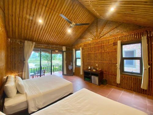 a bedroom with two beds and a balcony at Mường Village Ninh Bình in Ninh Binh