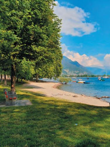 MinusioにあるResidenza Arazzoの水にボートが浮かぶビーチの横にある公園のベンチ