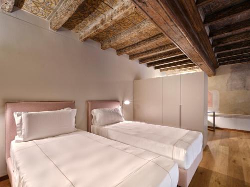 two beds in a room with exposed ceilings at Palazzo Del Carretto-Art Apartments and Guesthouse in Turin