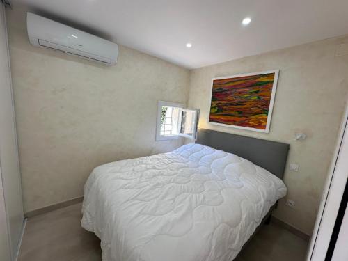 - une chambre avec un lit blanc et un tableau dans l'établissement Magnifique villa, Port Nature, Village Naturiste, 2 pièces, 36m2, 150m de la plage, au Cap d'Agde