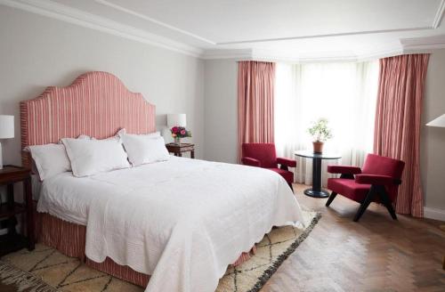 a bedroom with a large bed and two red chairs at Oakley Court in Windsor