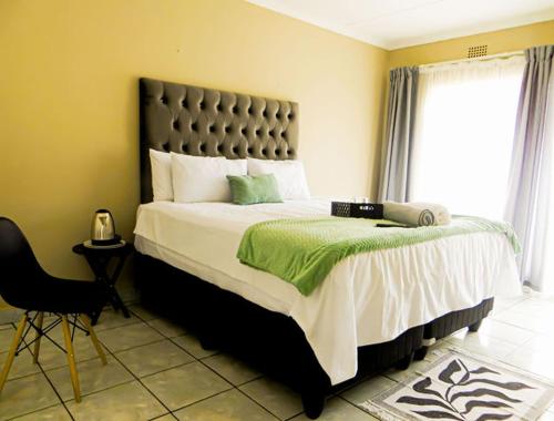 a bedroom with a large bed and a chair at HavenNest in Rustenburg