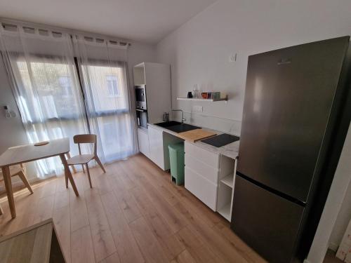 Il comprend une cuisine équipée d'un réfrigérateur, d'une table et de chaises. dans l'établissement Studio neuf climatisé wifi 27m2, à Oullins