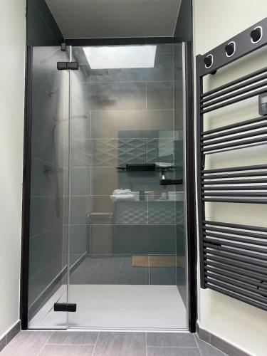 La salle de bains est pourvue d'une porte de douche en verre. dans l'établissement Maison L 'escapade, à Saint-Julien