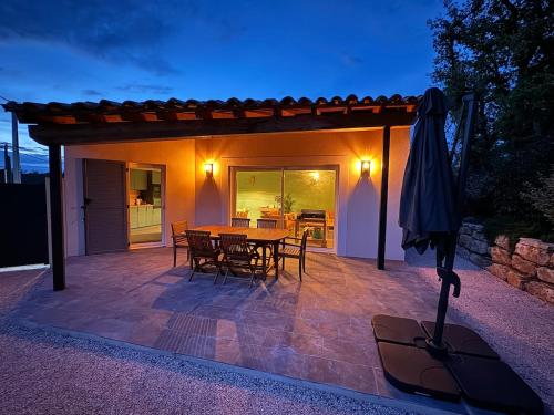 un patio avec une table, des chaises et un parasol dans l'établissement Maison L 'escapade, à Saint-Julien
