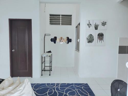 a white room with a door and a blue rug at A&W Homestay, Vista Perdana, Miri in Miri