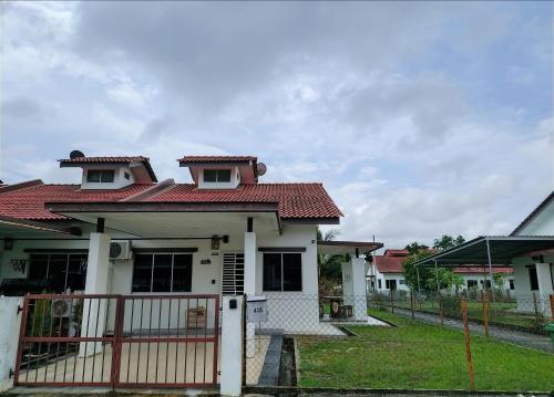 a white house with a red roof and a gate at A&W Homestay, Vista Perdana, Miri in Miri