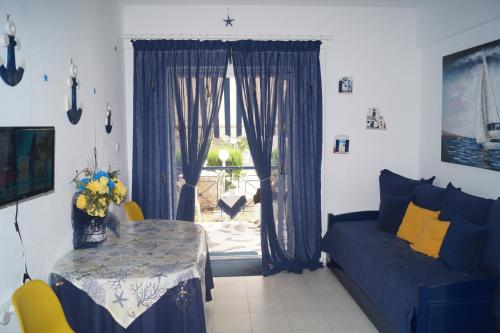 un soggiorno con divano blu, tavolo e finestra di Fay's paradise a Polykhrono