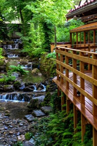 a wooden bridge next to a stream with a waterfall at Hotel Promyk Wellness & Spa in Karpacz