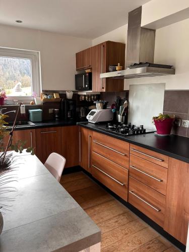 une cuisine avec des placards en bois et des comptoirs noirs dans l'établissement Appartement family, à Taninges
