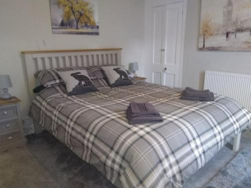 a bed with a plaid blanket and pillows on it at Pankhurst, Louth in Louth