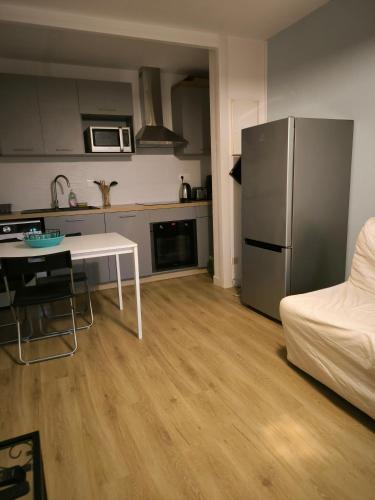 une cuisine avec une table et un réfrigérateur en acier inoxydable dans l'établissement t2 spacieux proche zénith&aéroport&purpan, à Toulouse