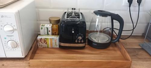 a coffee maker on a wooden tray next to a microwave at Къща за гости Веселина - Ивайловград in Ivaylovgrad