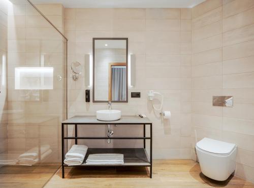 a bathroom with a sink and a toilet and a mirror at Radisson Hotel & Spa Gyumri in Gyumri