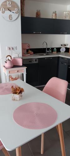 een keuken met een witte tafel en roze stoelen bij Lilas in Giromagny