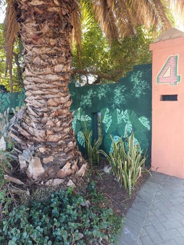a palm tree next to a wall with the number four at A Jungle House in Somerset West