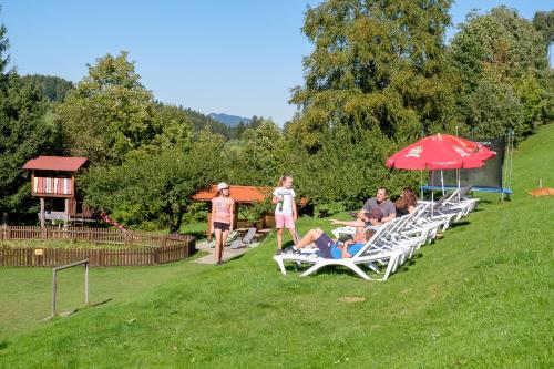 a group of people sitting on lawn chairs under an umbrella at Gästehaus Schlegel in Gunzesried