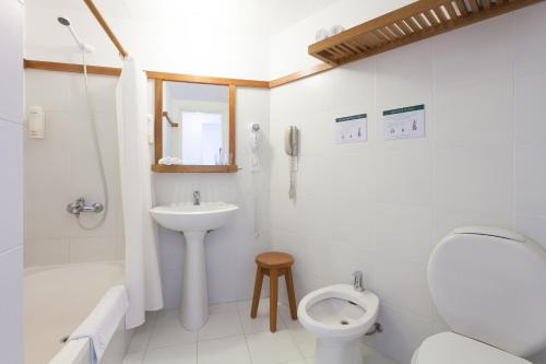 Baño blanco con aseo y lavamanos en Hotel Las Olas Resort, en Punta del Este