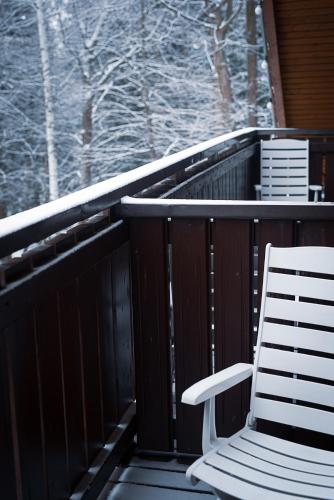 two chairs sitting on a deck in the snow at Hotel Promyk Wellness & Spa in Karpacz