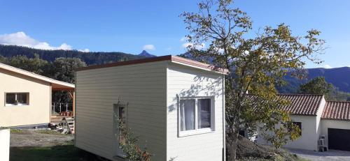 a small white and gray building next to a tree at Tiny House lumineuse et ressourçant in Le Brusquet