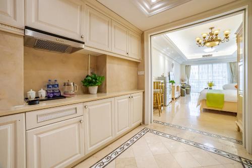 a kitchen with white cabinets and a room with a bed at WAIFIDEN Guangzhou HaiZhu Square WanYi Apartment in Guangzhou