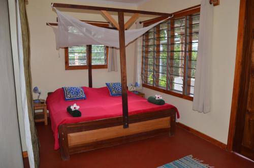 a bedroom with a red bed with a canopy at Milemeleni Guesthouse in Lushoto