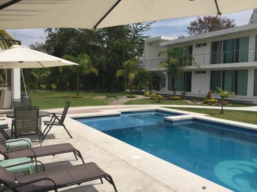 a pool with chairs and umbrellas next to a house at Quinta Souffle in Xochitepec