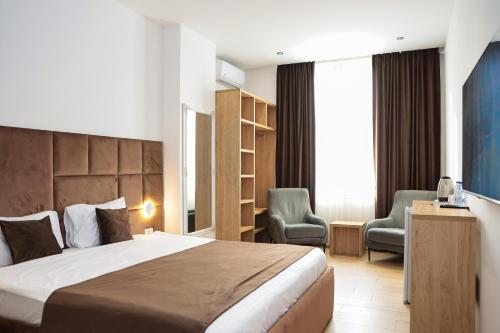 a hotel room with a bed and two chairs at Hotel Privé in Peje
