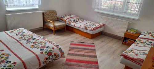 a bedroom with two beds and a chair and a rug at Chalupa Kalameny in Kalameny