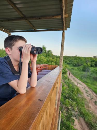 a man is looking through a binoculars on a table at Kingfisher Creek Safari Lodge in Hoedspruit