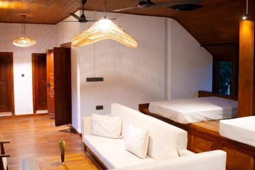a room with two beds and a couch and a chandelier at Tribe Wilpattu - Eco Lodge in Wilpattu