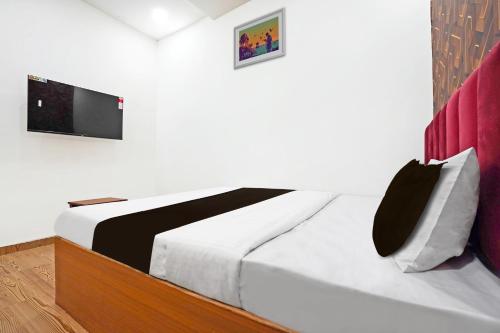 a bedroom with a bed with a tv on the wall at Super Hotel O Sunshine Villa in Nagpur