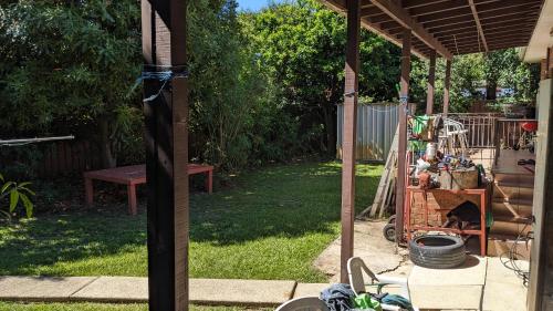 a backyard with a porch with a table and a bench at BIDWILL GARDENS ON MIDDLETON - 2 Rooms A Private Room with a King-Size Bed or Open Lounge Room Floor Mattress SHARED Bathroom FREE Kitchen Essentials FREE Laundry Facilities Fast NBN WIFI HDTV NETFLIX, YOUTUBE, KAYO Meal and Transport Service Available in Bidwill