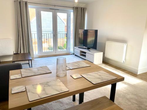 a living room with a wooden table and a television at New Modern 2 Bed with parking in BISHOPS STORTFORD, close to Stansted Airport! in Bishops Stortford