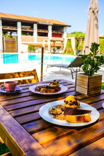 two plates of food on a wooden table next to a pool at Borgo Pallavicini Mori in Prima Porta