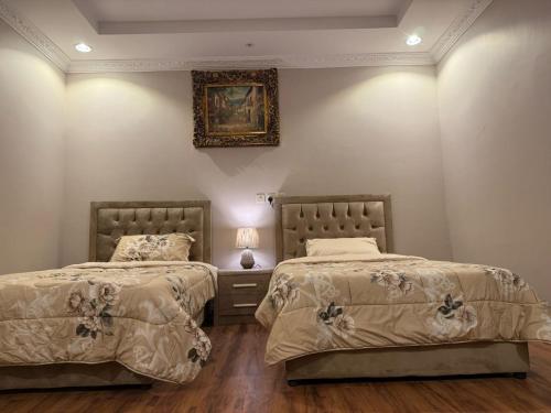 a bedroom with two beds and a picture on the wall at نزل العقيق بحي الجامعة in Medina