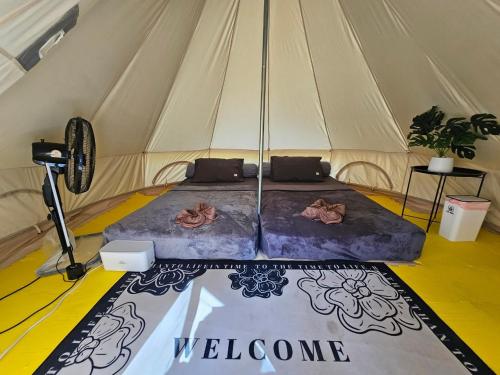 a bed in a tent with a welcome sign on it at Nahm Khao Sok Hostel and Camping in Khao Sok