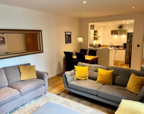 a living room with two couches and a kitchen at Oswald Apartment - Glasgow City Centre in Glasgow