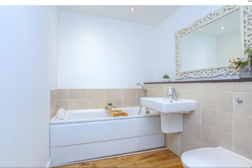 a bathroom with a tub and a sink and a mirror at Oswald Apartment - Glasgow City Centre in Glasgow