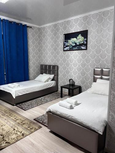 a bedroom with two beds and a blue curtain at Отель при ресторане Sultan Sarayi in Kostanay